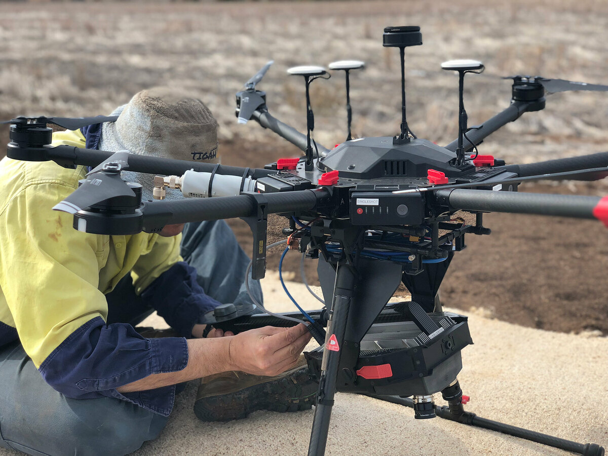 A person is sitting down fixing a drone.