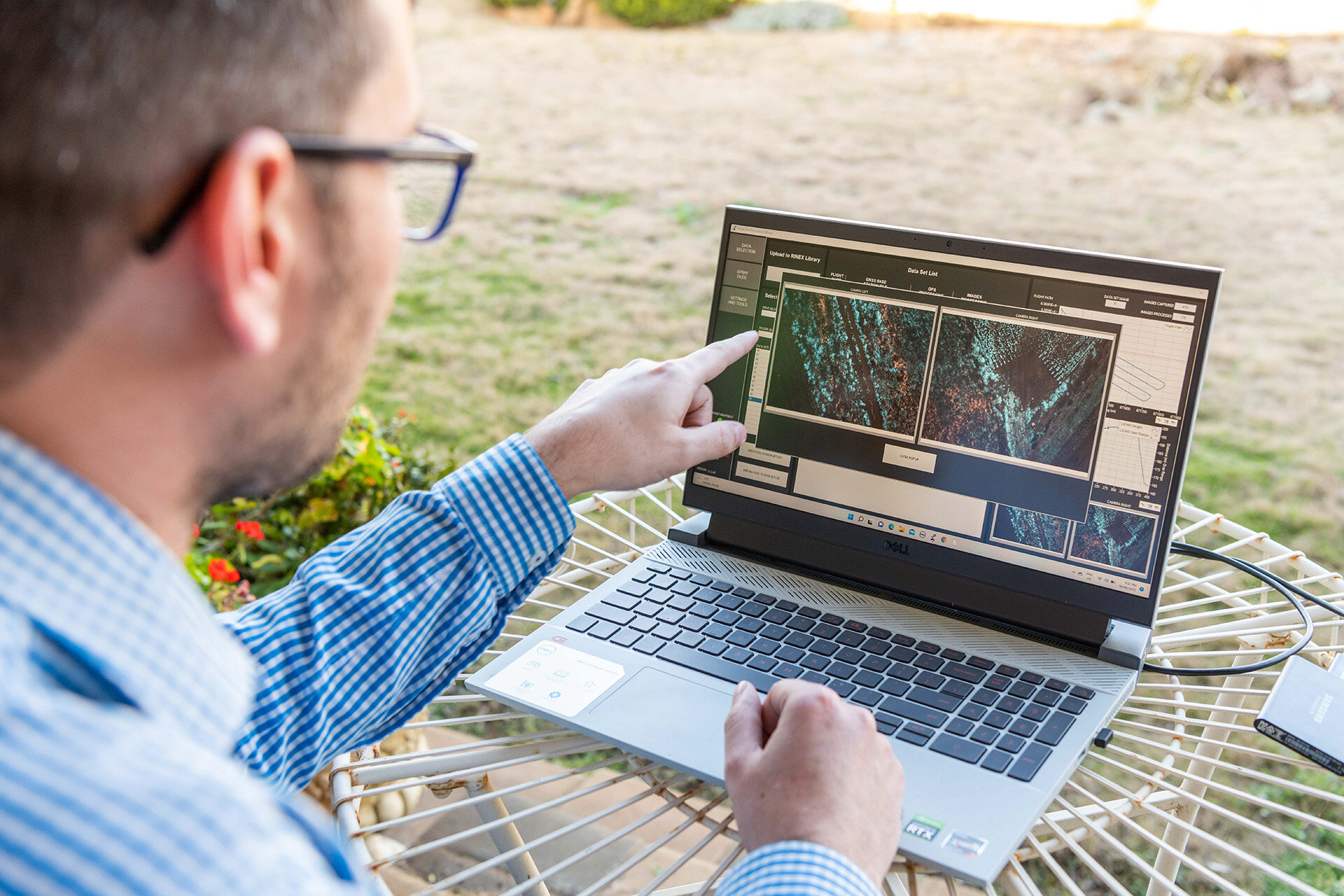 A man is pointing to a satellite view of weed mapping on his laptop computer